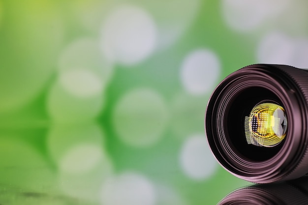 Matériel vidéaste et photographe. Lentilles sur la table sur fond de lampes lumineuses. Éblouissement et bokeh dans le reflet de la vitre de l'appareil photo.