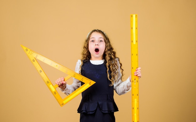 Matière scolaire de géométrie. Concept d'éducation et d'école. Concept intelligent et astucieux. Dimensionnement et mesure. Élève jolie fille avec une grande règle. La géométrie d'étude d'étudiant d'école. L'uniforme scolaire pour enfants tient la règle.