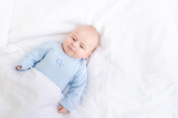 Matin bébé garçon sur le lit sous la couverture sommeil sain du nouveau-né