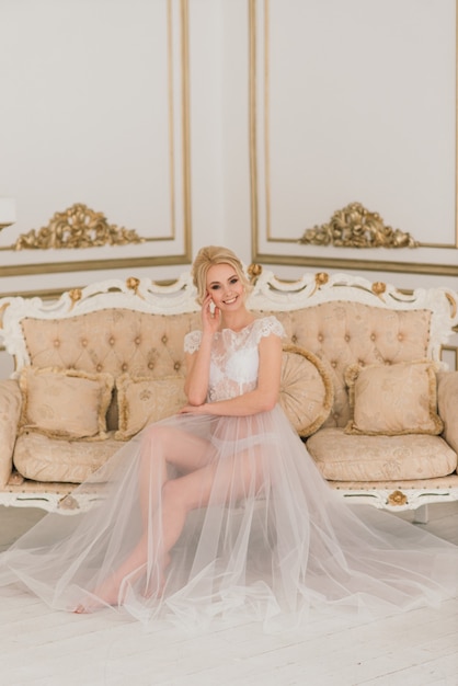 Matin d'une belle jeune mariée en robe boudoir. Studio, intérieur.