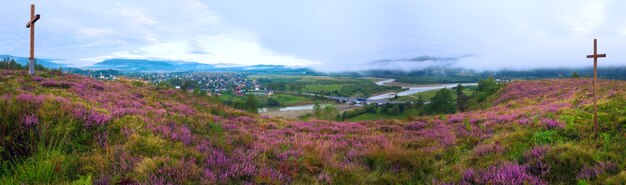 Matin brumeux d'été panorama des contreforts du pays avec fleurs de bruyère et croix en bois (oblast de Lviv, Ukraine) . Trois clichés piquent l'image.