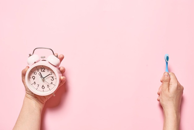 Matin concept réveil rose et une brosse à dents dans les mains d'une jeune femme