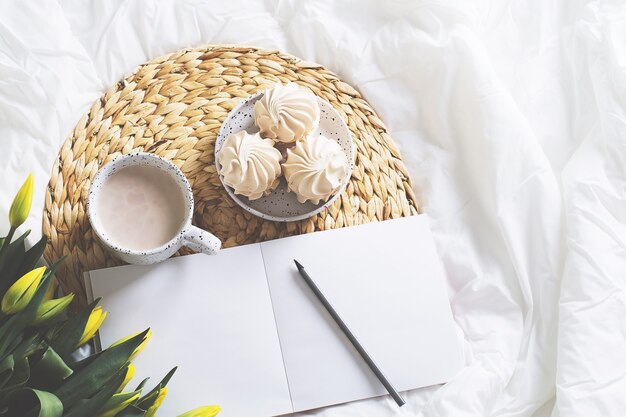 Matin nature morte avec tasse de café, tulipes et carnet de croquis. vue de dessus