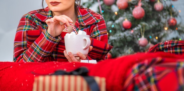 Matin de Noël, fille en pyjama avec une tasse de cacao chaud avec des guimauves. Mise au point sélective.