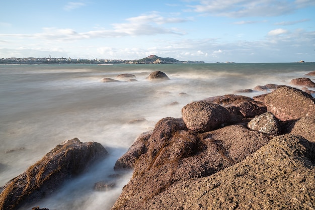 Le matin, le soleil brille sur les rochers et les vagues sur la plage ;