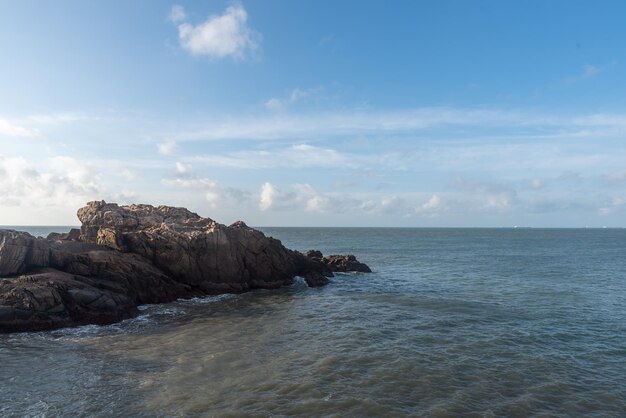 Le matin, le soleil brille sur les rochers et les vagues sur la plage.