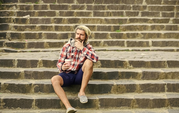 Matin vibes touriste se détendre dans les escaliers boire du thé café sur le pouce homme avec une tasse de café à l'extérieur bel homme barbu calme à l'extérieur avec une tasse de café homme buvant du café chaud