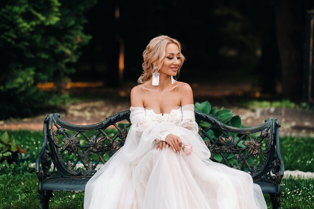 Matinée de la mariée dans le jardin. Portrait d'une jeune mariée regardant sa robe de mariée, accrochée à un arbre de jardin.