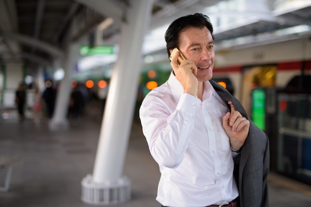 Mature bel homme d'affaires parlant au téléphone à l'extérieur