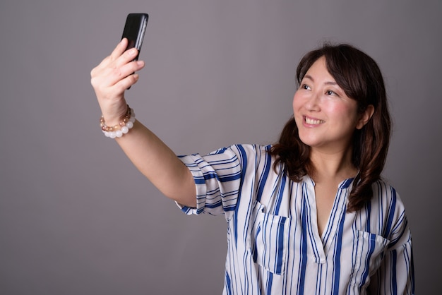 mature belle femme d'affaires asiatique à l'aide de téléphone mobile