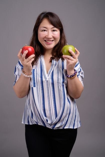 mature belle femme asiatique tenant des pommes