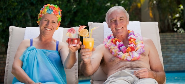 Photo mature couple buvant un cocktail au bord de la piscine