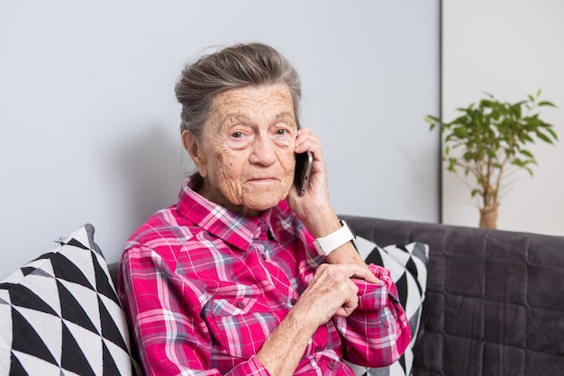 Mature heureux joie sourire actif cheveux gris rides du Caucase femme assise à la maison dans le salon sur le canapé