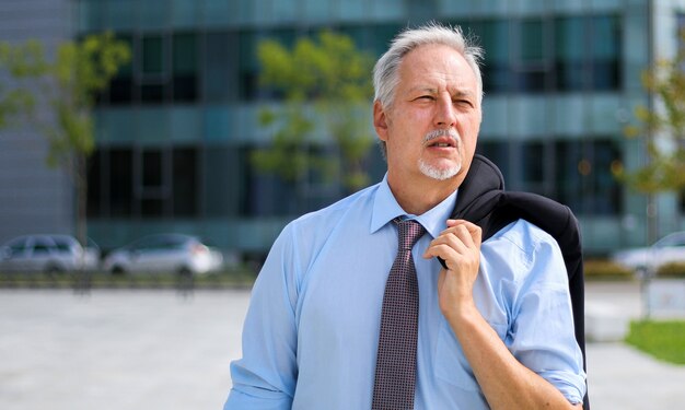 Mature Homme d'affaires marchant en plein air dans un cadre urbain moderne