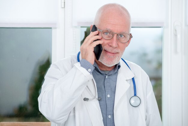 Mature médecin au téléphone dans son bureau