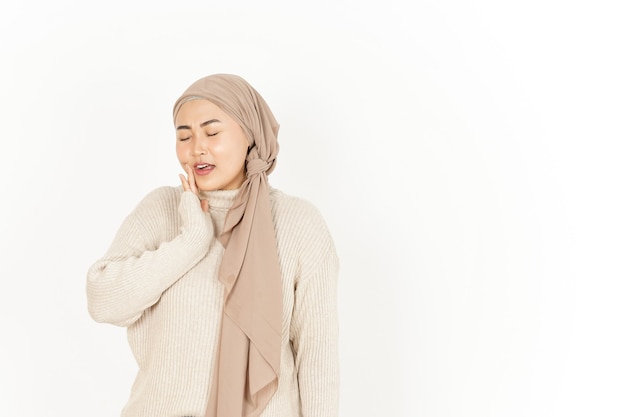 Maux de dents avec la main sur la joue de la belle femme asiatique portant le hijab isolé sur fond blanc