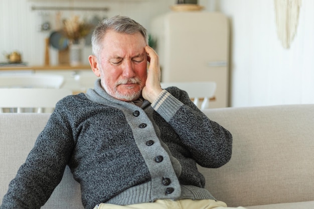 Maux de tête douleur malheureux homme âgé d'âge moyen souffrant de maux de tête malade se frotter les tempes à la maison