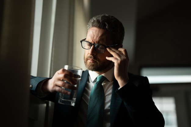 Maux de tête fatigués et fatigue des yeux d'un homme d'affaires avec un ordinateur portable avec un épuisement psychologique et une fatigue oculaire