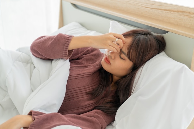 Photo maux de tête femme asiatique et dormir sur le lit