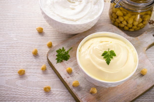 Mayonnaise végétalienne à base de pois chiches et de legemus avec un pot d'aquafaba en arrière-plan œuf ou ingrédient sans lait