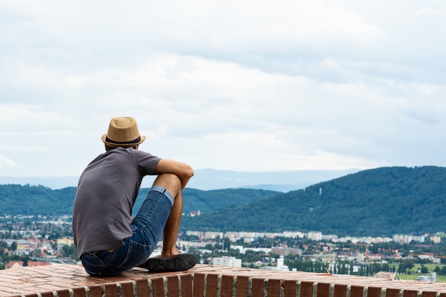 mec assis sur le bord d&#39;un grand bâtiment et regarde au loin