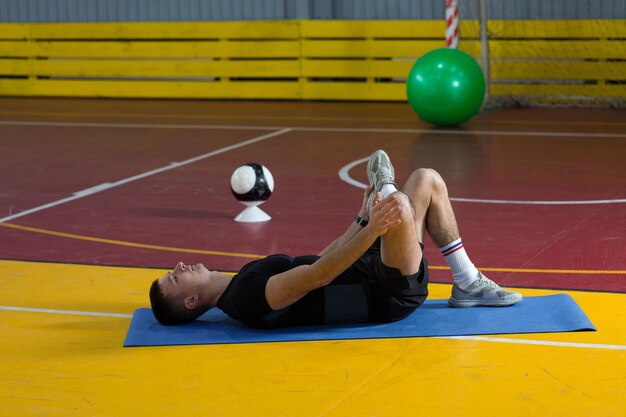 Mec athlétique en vêtements de sport et fitness tracker faisant des exercices dans la salle de gym.