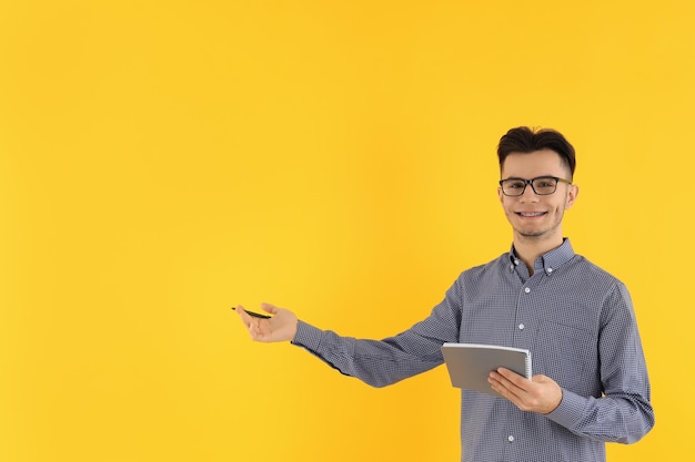 Mec attirant avec cahier et stylo sur fond jaune