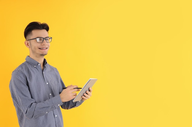 Mec attirant avec cahier et stylo sur fond jaune