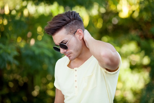 Mec attrayant dans le parc avec des lunettes de soleil