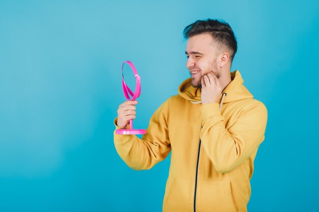 le mec au sweat jaune se regarde dans le miroir rose