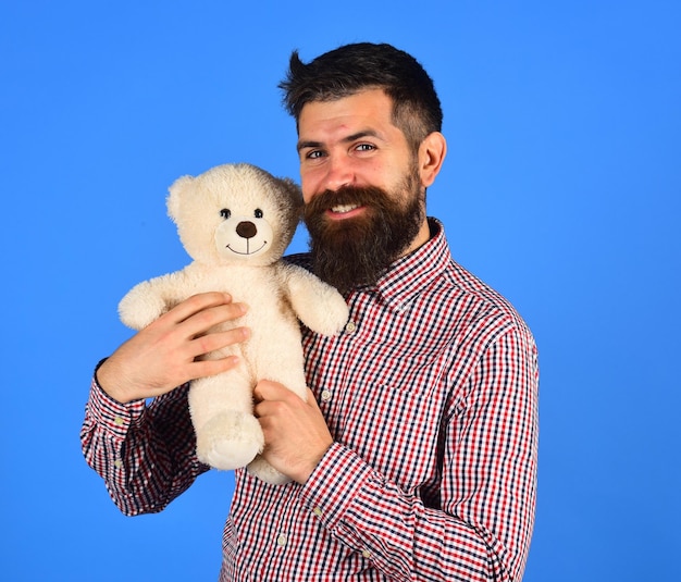 Un mec au visage heureux joue avec une peluche blanche