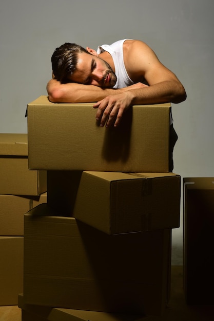 Un mec aux mains musclées fait la sieste sur des boîtes tient la tête