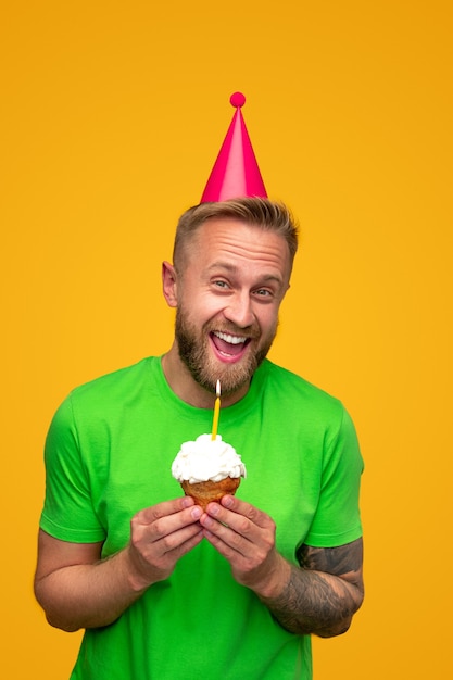 Mec barbu excité avec cupcake d'anniversaire