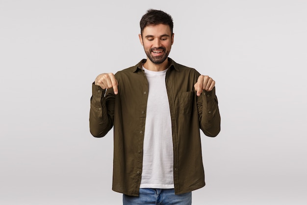 Mec barbu en manteau brun pointant vers le bas