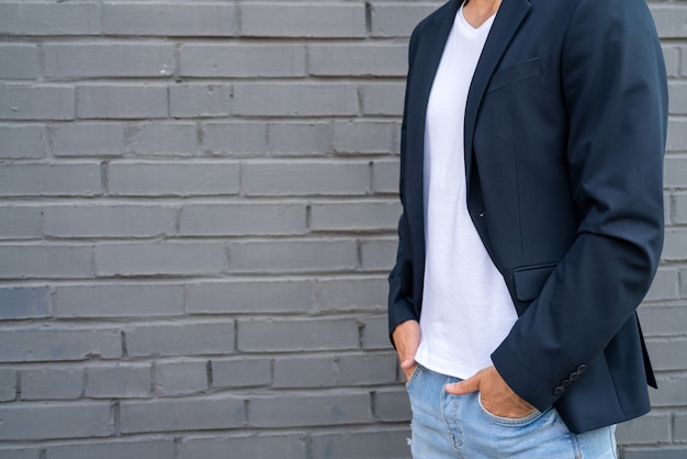 Mec blanc dans un T-shirt et une veste blancs. Modèle masculin sur fond de mur.