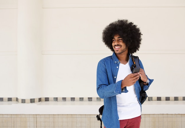 Mec cool souriant avec sac et téléphone portable