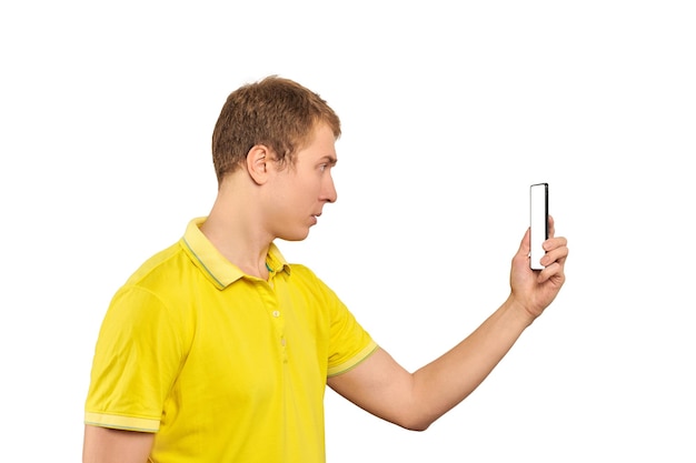 Mec drôle en T-shirt jaune prenant des photos à l'aide d'un gars de smartphone avec une maquette blanche de téléphone portable