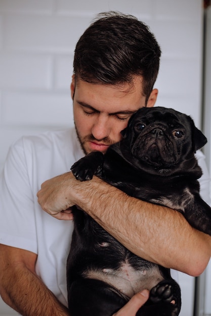 Le mec embrasse doucement un chien carlin