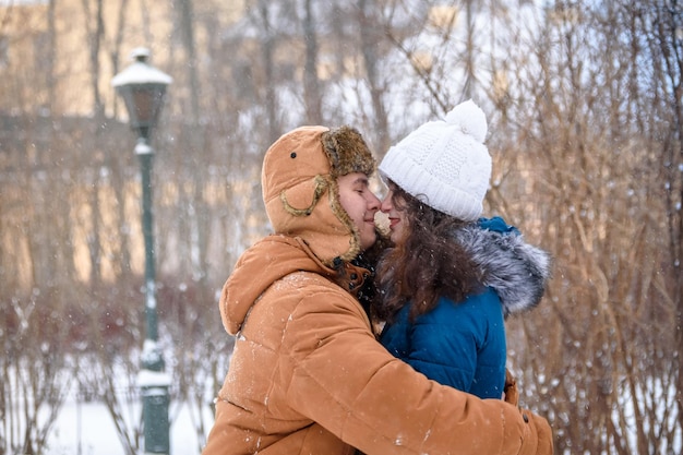 Un mec et une fille s'embrassent dans un parc d'hiver