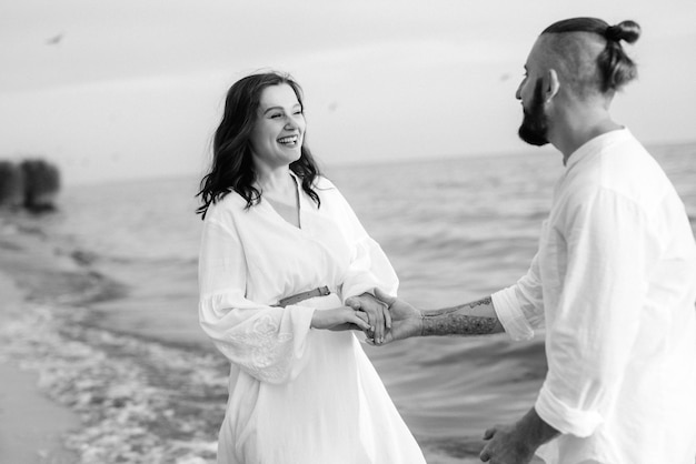 Un mec avec une fille en vêtements blancs au bord de la mer