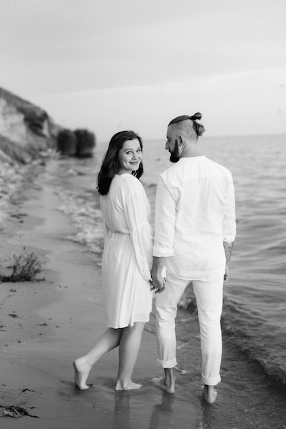 Un mec avec une fille en vêtements blancs au bord de la mer