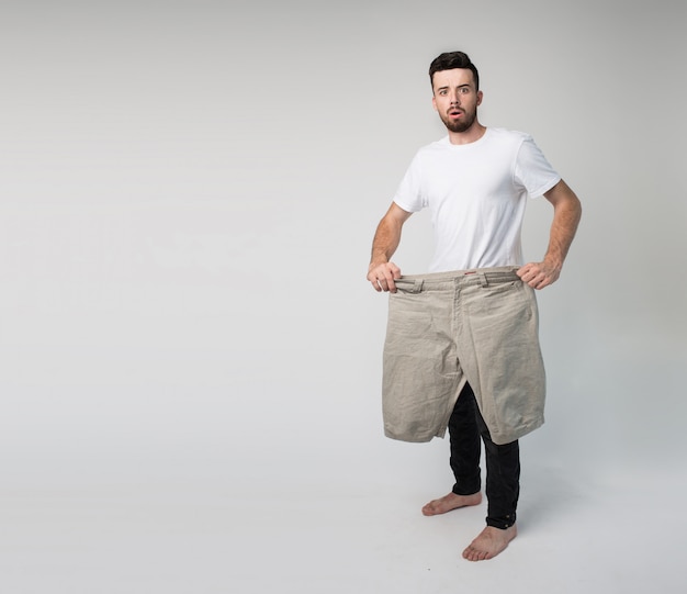 Mec avec un grand et grand pantalon en mains posant devant la caméra