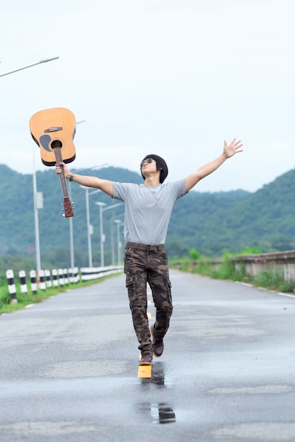 Mec avec guitare debout sur le barrage, pantalon cargo