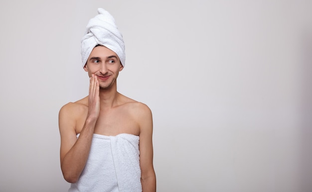 Le mec mignon après la douche dans une serviette sur la tête.