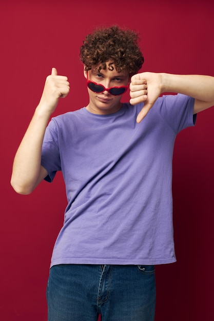 Mec mignon aux cheveux roux dans un t-shirt violet avec des lunettes de soleil posant