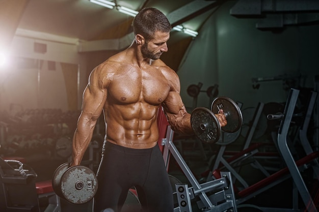 Mec musclé bodybuilder faisant des exercices avec haltère dans la salle de gym