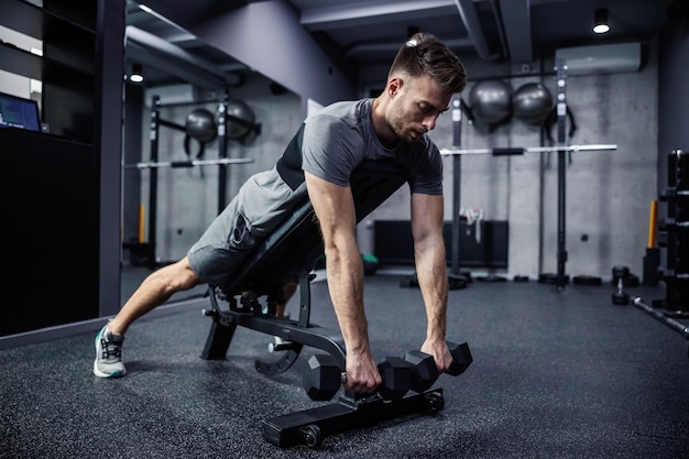 Un mec musclé soulève un haltère en position allongée sur un banc de gym