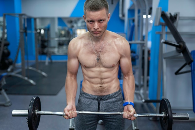 Photo un mec musclé avec un torse nu s'entraîne à soulever la barre vers les biceps