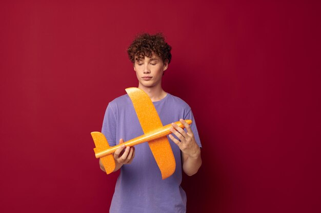 Mec pervers avec un avion jouet dans un t-shirt violet fond rouge inchangé