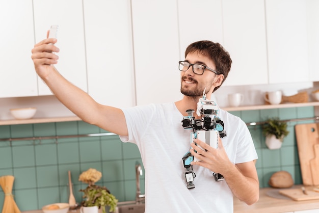 Un mec posant avec un robot dans une cuisine légère moderne